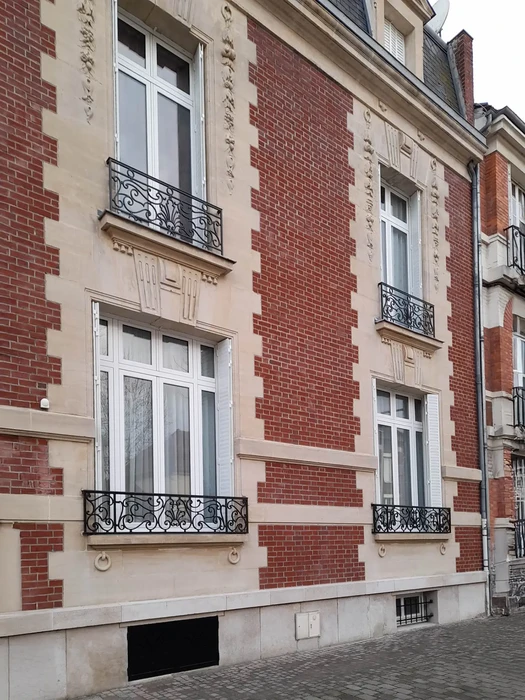Façade d'immeuble résidentiel avec alternance de briques rouges et pierres de taille beige