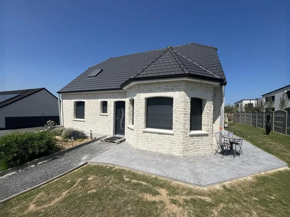 Maison individuelle moderne en pierre blanche avec toiture ardoise, située dans lotissement résidentiel