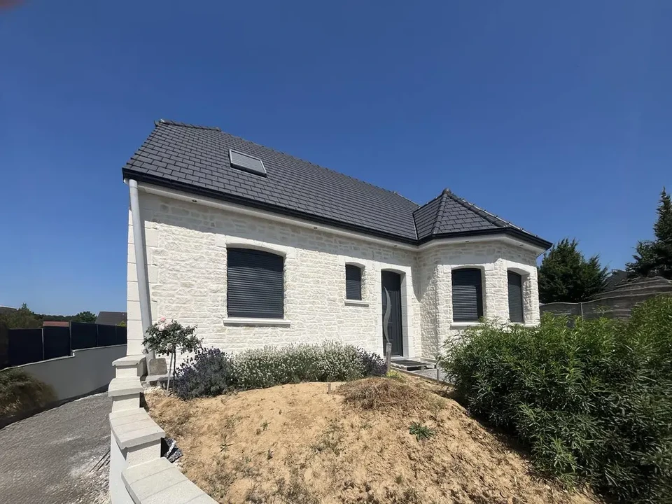 Maison individuelle moderne en pierre blanche avec toiture ardoise, située dans lotissement résidentiel