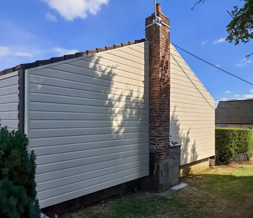 Deux ouvriers en vêtements haute visibilité installent des panneaux d'isolation thermique extérieure sur façade de maison individuelle
